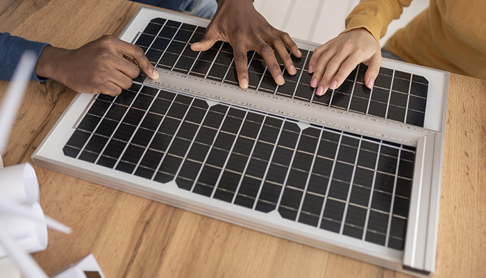 Manos de dos personas en un panel solar, enseñando y mostrando lo que es un panel solar.